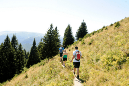 three young adults walking on a hillside