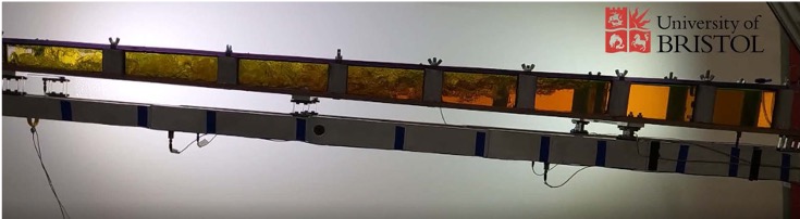 Picture shows an experimental study  - part of the EU SLOWD project - into the effect of fluid sloshing on the dynamic characteristics of a wing. The beam is a scaled version of a modern aircraft wing structure and the fluid is scaled to mimic the behaviour of the fuel undergoing the response to atmospheric turbulence. The photo shows the motion just after the release of the structure following a vertical deflection, and the turbulent motion in some parts of the fluid can be clearly seen